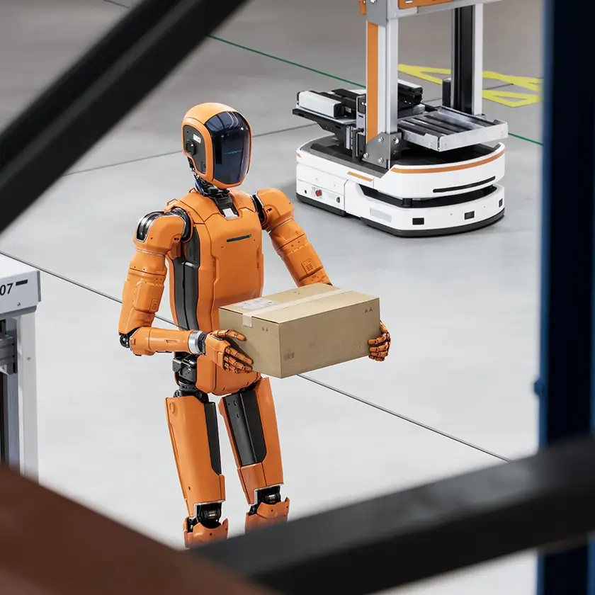 Orange humanoid robot carrying box